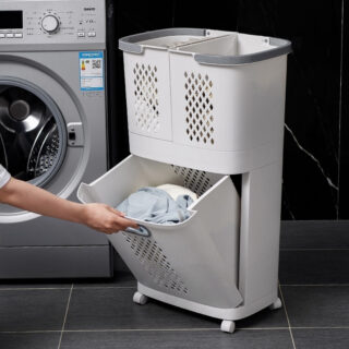 Photo d'un panier à linge trois compartiments en plastique devant une machine à laver