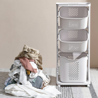 Photo d'un panier à linge à trois compartiments superposés, avec une pile de linge à côté