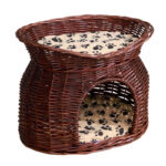 On voit un panier pour chat en osier l'une des assise est en hauteur sur le dessus, et l'autre cachée sous la première. Le panier pour chat est en osier marron avec des coussins.