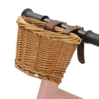 Un panier de vélo en osier beige fixé avec des sangles sur le guidon d'un vélo rose.