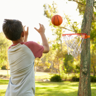 enfant qui joue dans un parc avec le cerceau de basket qui est accrocher sur un arbre