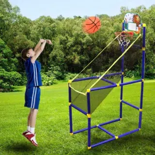 Enfant habillé en basketteur dans la pelouse en train de lancer un ballon dans un panier de basket en jeu d'arcade avec filet