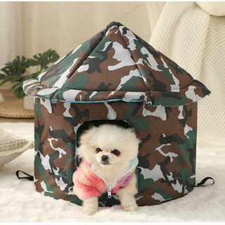 On voit un chihuahua blanc habillé en rose qui est dans un panier pour chien en forme de dôme, étanche et imprimé d'un motif treillis militaire.