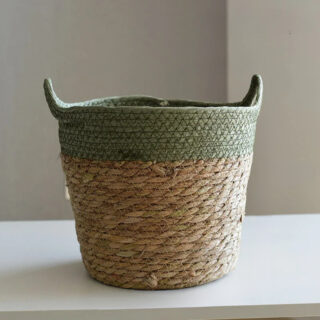 Panier cache pot en osier style artisanal ici posé sur une table blanche.