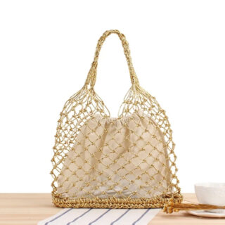 Panier de plage avec une armature solide dorée ici posé sur une table avec un fond blanc.
