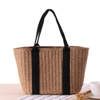 Panier de plage solide en rotin posé sur une table sur un fond blanc.