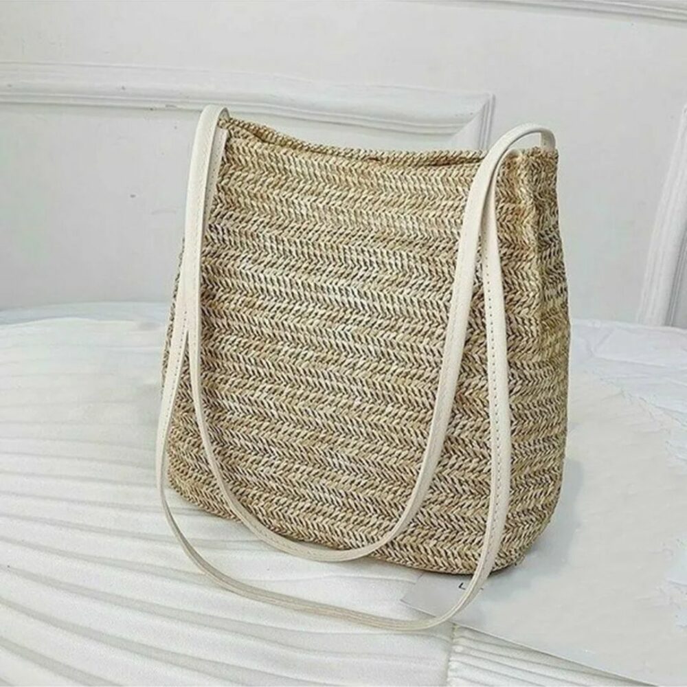 Panier de plage en paille avec lanières sur fond blanc