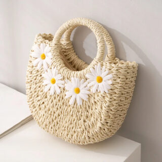 Panier de plage avec des motifs de marguerites ici posé sur une table blanche.